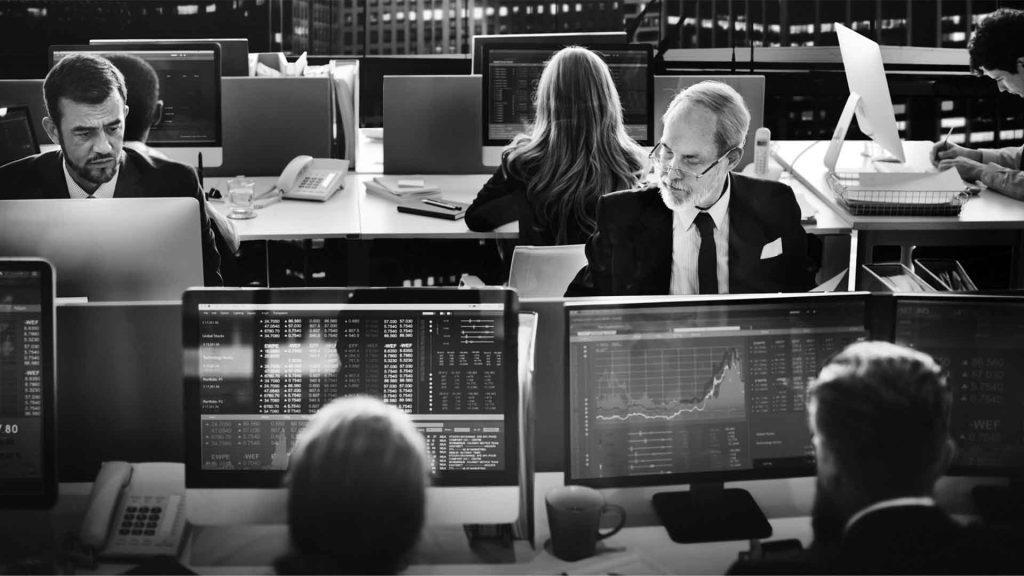 Vários traders profissionais em sala executando operações de day trade.